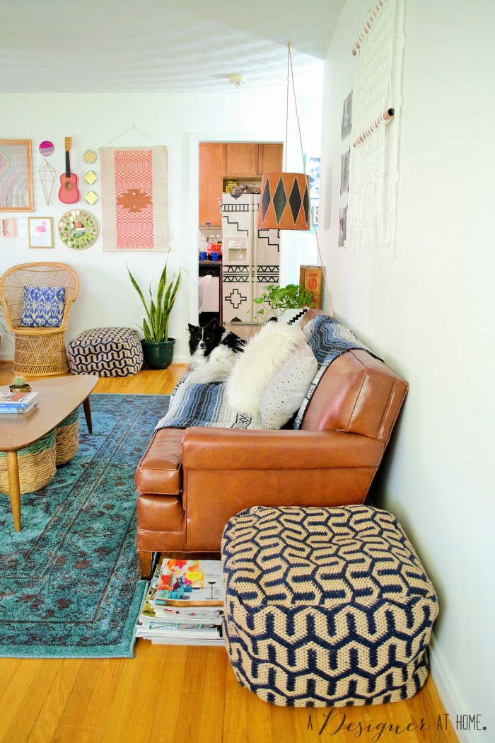 view from the front door included a really cool vinyl sofa and bright gallery wall a casually boho eclectic decorated space the living room of a 1950's brick ranch