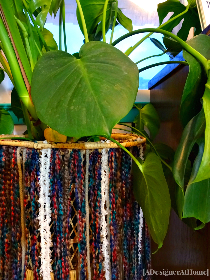 split leaf pothos in wicker plant stand with diy yarn fringe skirt