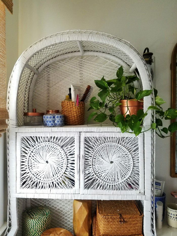 white painted wicker cabinet with baskets, thrifted containers to hide all of the bathroom essentials