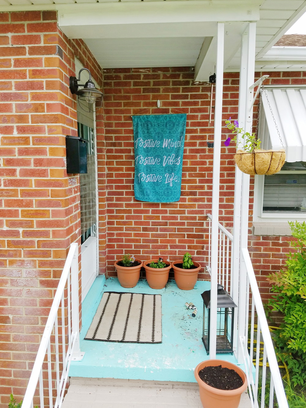 Aqua front porch. Bright paint with brick home. Lifestyle boho porch flag @adesignerathome